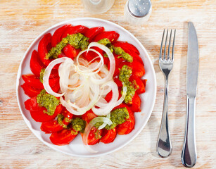 Sliced fresh tomatoes served with basil pesto sauce and onion. Italian style appetizer