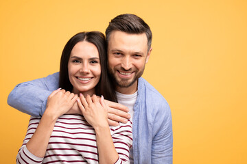 Fototapeta premium A married couple poses together with affection, showcasing their connection. They smile brightly while embracing, creating a friendly and warm atmosphere in a vibrant setting, copy space