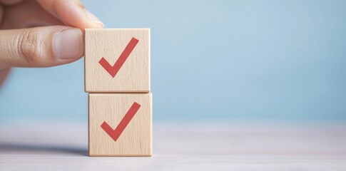 Hand Holding Wooden Blocks With Check Marks on Soft Blue Background