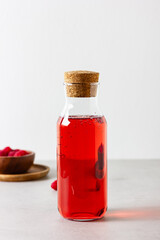 Raspberry drink in the glass bottle on the light background.