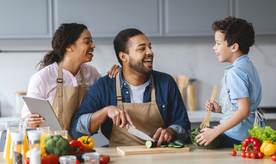 In a warm, inviting kitchen, a father happily prepares food while his wife and son share laughter...