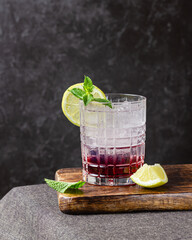 Cocktail with ice in a glass on a wooden cutting board