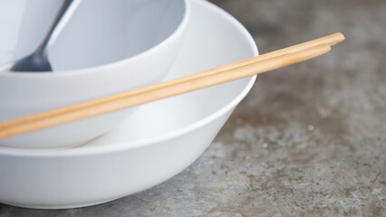 Empty white bowl and chopsticks on cement table background