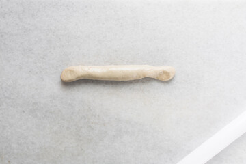 Overhead view of hand pulled noodles being stretched on a table, top view of biang biang noodles being stretched on a marble countertop, process of making biang biang mian