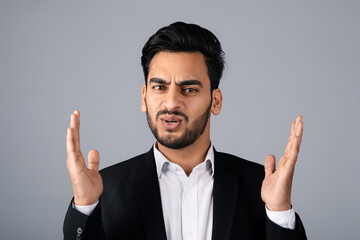 A Middle Eastern businessman in a suit conveys surprise with his hands raised. He is in a studio setting, focusing on entrepreneurial concepts and corporate strategies.