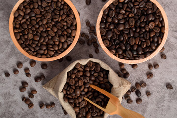 Roasted coffee beans in wooden bowl and sack isolated on dark cement background. Top view