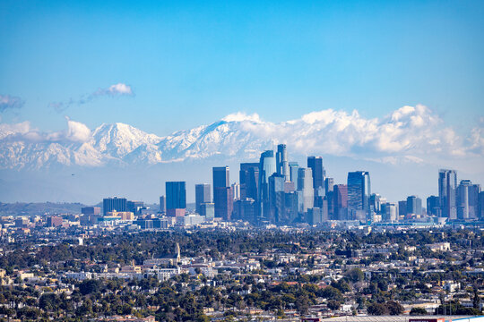 View over Los Angeles Skyline in California with snow covered mountains in the background. Visible are San Gabriel and San Bernardino mountains. 