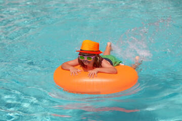 Children playing in pool. Child boy swim with float ring in swimming pool. Kids summer holidays and vacation concept. Happy little boy with inflatable ring in swimming pool.