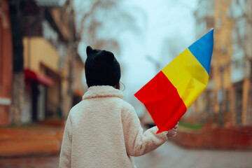 Child Holding a Flag Celebrating Romania. Romanian girl feeling patriotic during national holiday 
