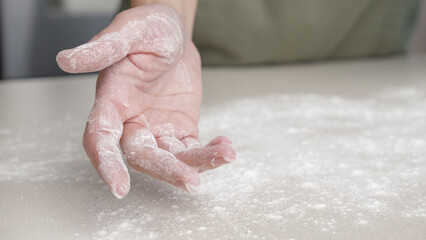 Fototapeta premium Hands, flour and baking by woman in a kitchen for bread, pizza or handmade food at home. Wheat, palm and female chef with messy fingers from cooking, fun and preparing diy, pasta or cake in her house