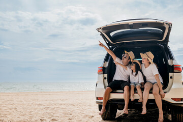 Tourism Day. Dad, mom and daughter enjoying road trip sitting on back car and pointing finger out...