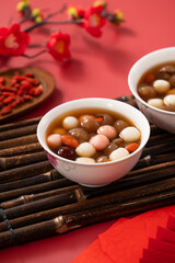 Red and white tangyuan with syrup soup, dried longan pulp, red dates for Chinese lunar new year.