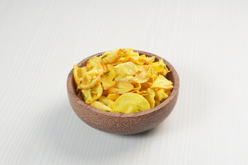 Cassava chips in a wooden bowl on a white plywood mat photographed with studio light