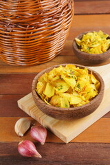 Cassava chips in a wooden bowl on a wooden base photographed with studio light with a traditional theme