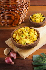 Cassava chips in a wooden bowl on a wooden base photographed with studio light with a traditional theme