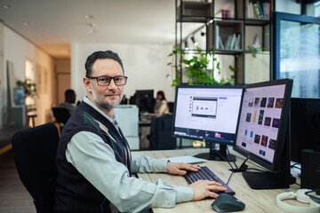Professional man working at dual monitors in modern office setup