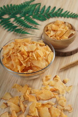 Cassava chips in a clear glass bowl on a plywood base photographed with studio light