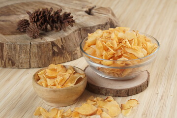 Cassava chips in a clear glass bowl on a plywood base photographed with studio light