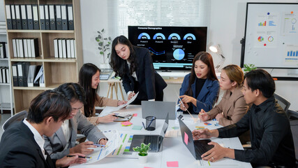 Business colleagues collaborating on data analysis, using laptops and documents to review...
