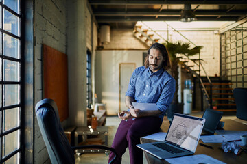 Fototapeta premium Architect analyzing blueprints in industrial office space