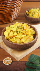 Cassava chips in a wooden bowl on a wooden base photographed with studio light with a traditional theme