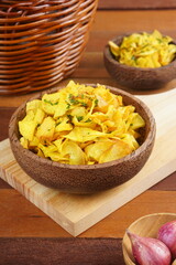 Cassava chips in a wooden bowl on a wooden base photographed with studio light with a traditional theme