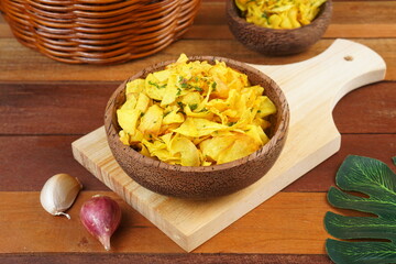 Cassava chips in a wooden bowl on a wooden base photographed with studio light with a traditional theme