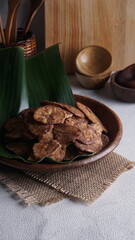 Indonesian chocolate flavored banana chips on a clay plate with a traditional property theme photographed with studio light