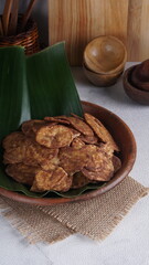 Indonesian chocolate flavored banana chips on a clay plate with a traditional property theme photographed with studio light
