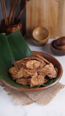 Indonesian chocolate flavored banana chips on a clay plate with a traditional property theme photographed with studio light