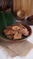 Indonesian chocolate flavored banana chips on a clay plate with a traditional property theme photographed with studio light