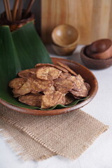 Indonesian chocolate flavored banana chips on a clay plate with a traditional property theme photographed with studio light