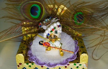 Decorative statue of Hindu God Lord Krishna also known as Bal Gopal sitting on his throne on Janmashtami festival. Selective focus on lord Krishna on White background