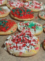 Child decorated cookies with Christmas colors of red, green, and white, adorned with buttercream icing and decorative sprinkles. Demonstrating a popular holiday family tradition of cookie making.