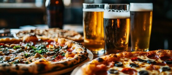 Diverse pizza selection and beer glasses on table in cozy restaurant setting with blurred background, inviting ambiance