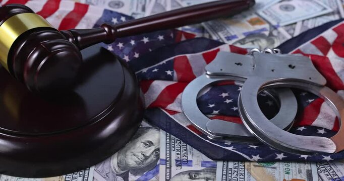 Justice gavel rests of cash with handcuffs an American flag, symbolizing law, justice system concerns