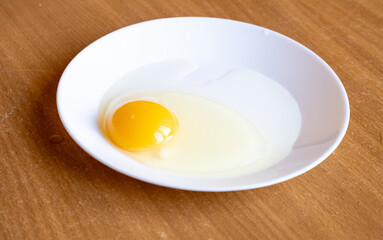 Raw egg in a plate on the table.Preparing breakfast.