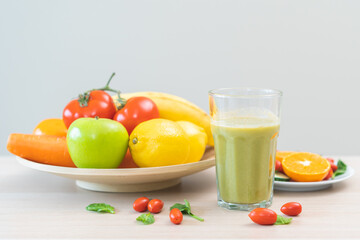 Green detox juice in glass jars, bottle of vegetable fresh ingredients on table, carrot smoothie for diet, drinking healthy meal food for weight loss. Detox breakfast, isolated on background.