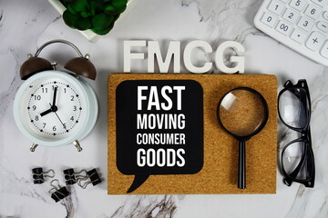 FMCG - Fast Moving Consumer Goods acronym with calculator, alarm clock and magnifying glass, Business and Financial concept background