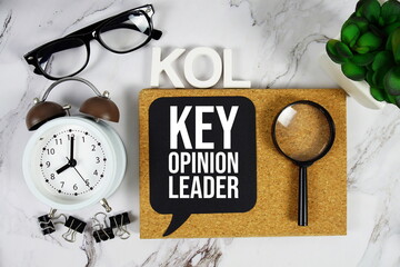 KOL - Key Opinion Leader acronym with alarm clock and magnifying glass, business concept background