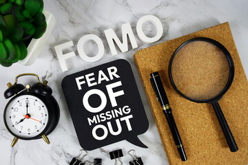 FOMO - Fear Of Missing Out acronym with calculator, alarm clock and magnifying glass, business and...