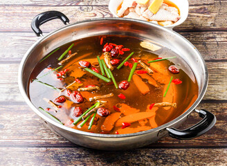 Huadiao Drunken Chicken Hotpot topping with scallions and red date or jujube served in steel pot isolated on wooden table side view of hong kong food