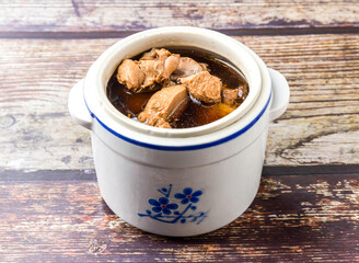 Maca snail head stewed in chicken soup served in clay pot broth isolated on wooden table side view of hong kong food