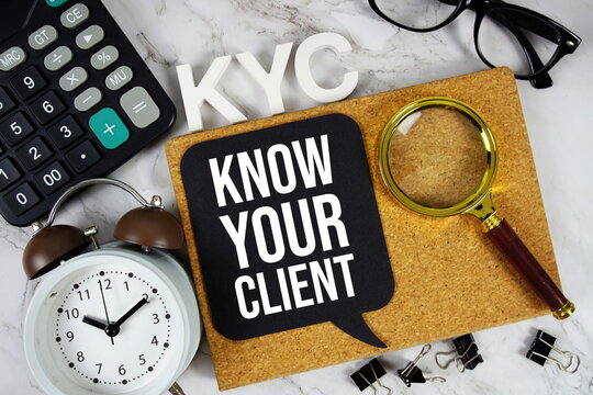 KYC - Know Your Client acronym with calculator, alarm clock and magnifying glass, business concept background