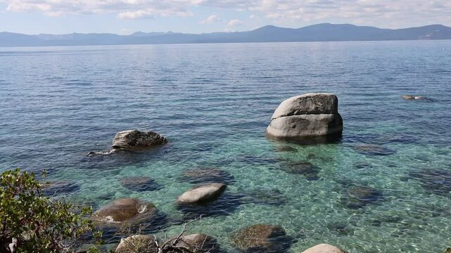 Serene scene at Lake Tahoe with crystal clear water and sun reflecting in the waves. 
