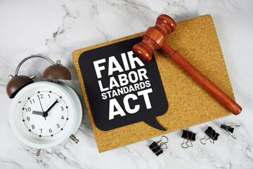 Fair Labor Standards Act text on speech bubble with alarm clock and wooden gavel on marble...
