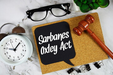 Sarbanes-Oxley Act text on speech bubble with alarm clock and wooden gavel on marble background