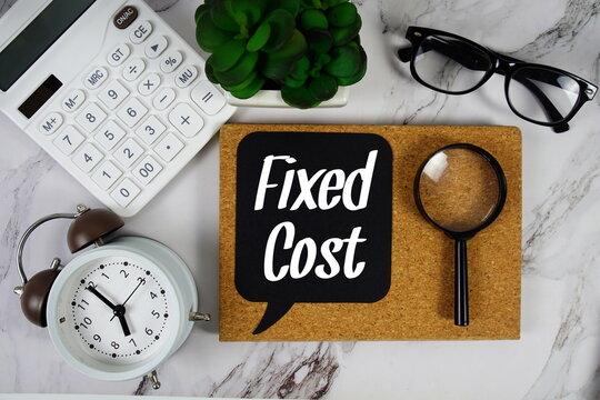 Fixed Cost text on speech bubble with alarm clock, calculator and magnifying glass on marble background