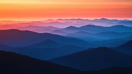 Fototapeta premium Experience the breathtaking view of a sunrise over rugged mountain peaks, where warm orange hues meet cool blue tones, showcasing nature s stunning beauty and tranquil at