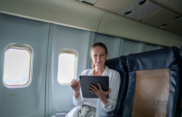 Tourist airplane cabin, engaged in a discussion productive conversation looking at the tablet screen is modern air travel, where passengers often utilize flight time to work or collaborate